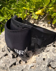 Black parawing stash belt with 'BRM' branding on a rock with greenery in the background