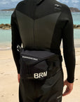Person wearing a black wetsuit and parawing belt on a beach